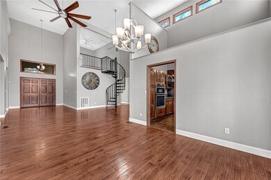 Unfurnished living room featuring a chandelier, a high ceiling, a ceiling fan, stairway, and dark wood-type flooring