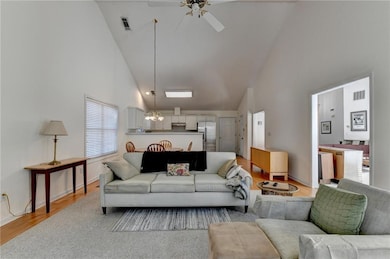 Living area featuring high vaulted ceiling, a ceiling fan, light wood-style flooring, and a chandelier