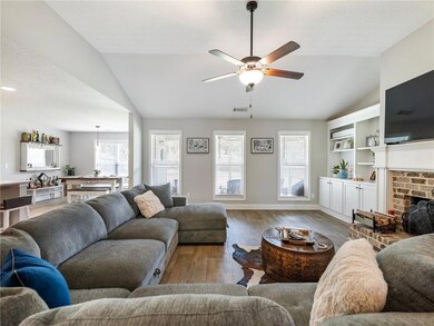 Living room with vaulted ceiling, a ceiling fan, wood finished floors, a fireplace, and baseboards