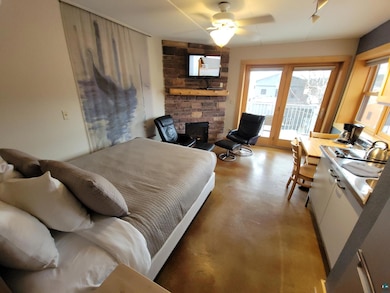 Bedroom with ceiling fan, a stone fireplace, and a