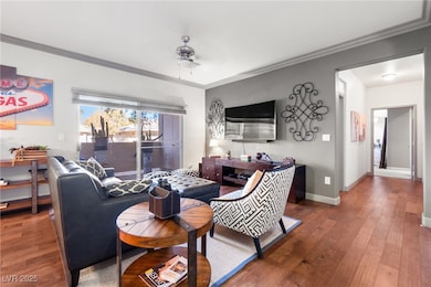 Bright and inviting living area featuring wood-style flooring, crown molding, and direct access to the private patio through sliding glass doors.