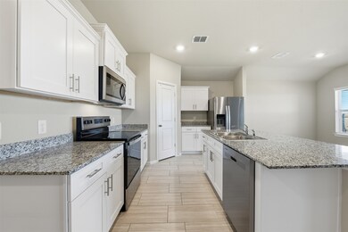 Kitchen featuring stainless steel appliances, white cabinets, recessed lighting, an island with sink, and light stone countertops