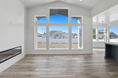 Unfurnished living room featuring light wood-type flooring, a glass covered fireplace, high vaulted ceiling, a chandelier, and recessed lighting