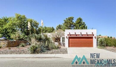 Pueblo-style home featuring driveway, a garage, and stucco siding