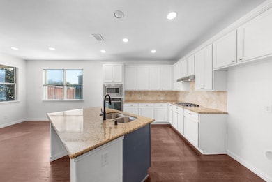 Kitchen with white cabinets, backsplash, light stone countertops, dark wood finished floors, and recessed lighting