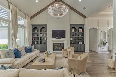 Spacious living room perfect for entertaining, featuring custom drapes, elegant ceiling beams, and custom built-in with space for decor and storage