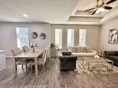 Living area featuring dark wood-style flooring, plenty of natural light, a tray ceiling, and recessed lighting