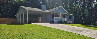 Ranch-style home with concrete driveway, covered porch, a chimney, and a carport