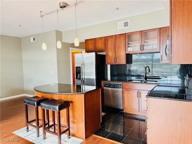 Kitchen featuring brown cabinetry, a kitchen breakfast bar, glass insert cabinets, tasteful backsplash, and stainless steel appliances