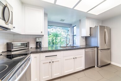 Kitchen featuring appliances with stainless steel finishes, white cabinets, decorative backsplash, and dark countertops