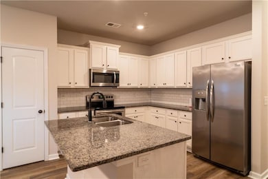 Kitchen featuring stainless steel appliances, dark stone countertops, tasteful backsplash, white cabinetry, and recessed lighting
