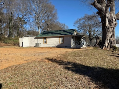 View of property exterior with a lawn and covered 