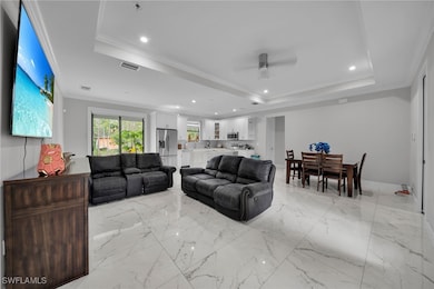 Living area with a tray ceiling, ceiling fan, rece