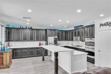 Kitchen featuring a center island with sink, recessed lighting, a breakfast bar, appliances with stainless steel finishes, and backsplash