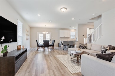 Living area with plenty of natural light, light wood-style flooring, recessed lighting, a chandelier, and stairway