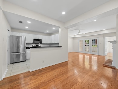 Kitchen featuring dark countertops, freestanding refrigerator, white cabinetry, light wood-style floors, and recessed lighting
