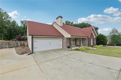 View of front of house featuring a garage, concrete driveway, a chimney, brick siding, and roof with shingles
