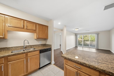 Kitchen featuring stainless steel dishwasher, dark stone counters, open floor plan, light tile patterned flooring, and recessed lighting