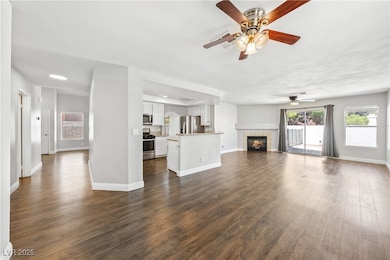 Unfurnished living room with a ceiling fan, dark w