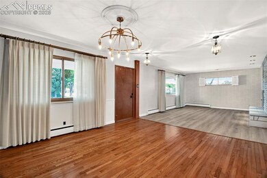 Unfurnished living room with a chandelier, wood finished floors, and a baseboard heating unit