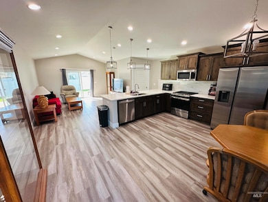 Kitchen featuring stainless steel appliances, open floor plan, tasteful backsplash, a peninsula, and hanging light fixtures