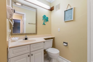 Half bathroom with vanity, toilet, baseboards, and ornamental molding