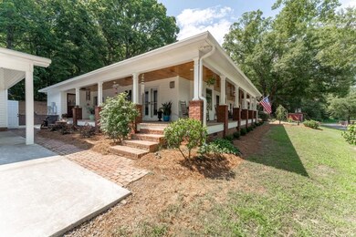 Side view of home with brick walkway between detached garage and carport.  The porch is so inviting.