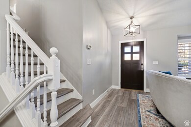 Foyer entrance featuring stairs, wood finished floors, healthy amount of natural light, and a chandelier