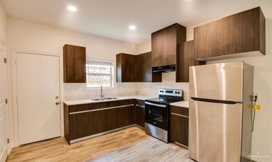Kitchen featuring dark brown cabinetry, light countertops, appliances with stainless steel finishes, light wood finished floors, and a sink