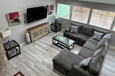 Living room with light wood-style floors, large windows, and built-in entertainment setup.