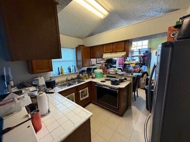 Kitchen with tile countertops, a textured ceiling,