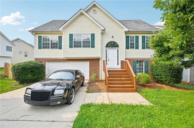 Raised ranch with driveway, an attached garage, and brick siding