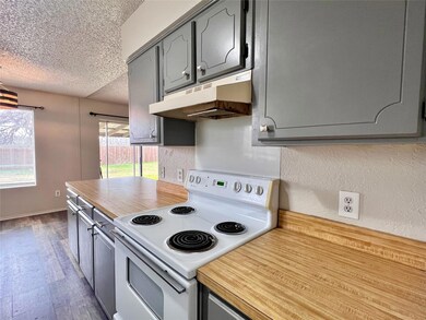 Kitchen with hardwood / wood-style flooring, white electric range, gray cabinets, and a textured ceiling
