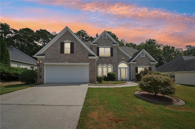 Traditional-style house with brick siding, driveway, a front yard, and a garage