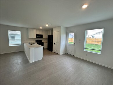 Kitchen with black appliances, a sink, baseboards, and light countertops