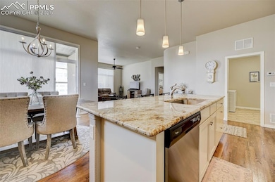 Kitchen with light wood-type flooring, stainless steel dishwasher, a sink, pendant lighting, and visible vents