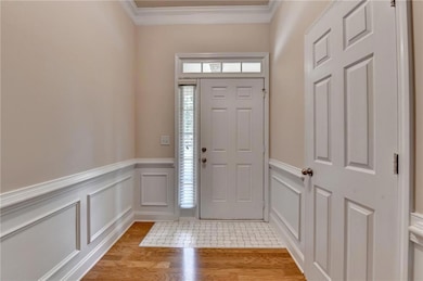 Entrance foyer featuring crown molding, wainscoting, and a decorative wall