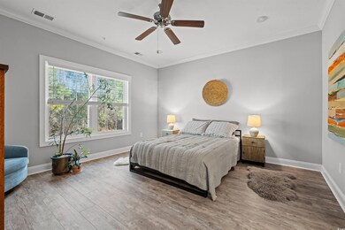 Bedroom with ornamental molding, wood finished floors, visible vents, and baseboards