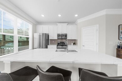 Kitchen featuring stainless steel appliances, decorative backsplash, ornamental molding, a breakfast bar area, and white cabinetry