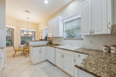Kitchen featuring white cabinetry, light tile patterned flooring, hanging light fixtures, dark stone countertops, and a chandelier