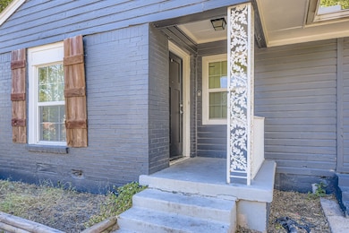 View of exterior entry with brick siding, a porch, and crawl space