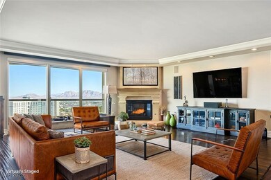 Living room with dark wood-style floors, a glass covered fireplace, and recessed lighting