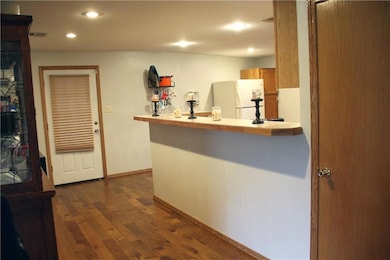 Kitchen featuring freestanding refrigerator, dark wood-type flooring, light countertops, recessed lighting, and a peninsula