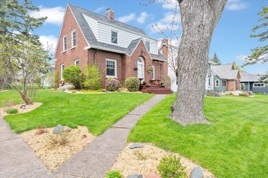 View of front facade featuring a chimney, brick siding, a front lawn, and a shingled roof