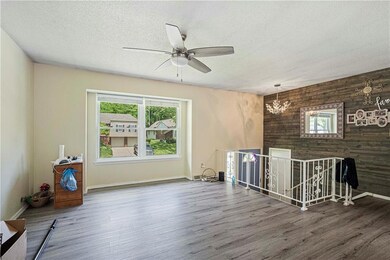 Spare room featuring hardwood / wood-style flooring, ceiling fan with notable chandelier, wood walls, and a textured ceiling