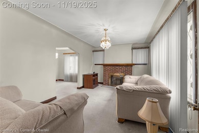 Carpeted living room with a brick fireplace, a chandelier, and arched walkways