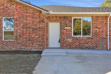 Entrance to property featuring brick siding and a shingled roof