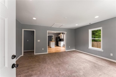 Carpeted spare room featuring baseboards, recessed lighting, and attic access