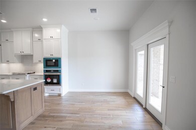 Kitchen featuring oven, black microwave, light wood-style flooring, white cabinetry, and recessed lighting