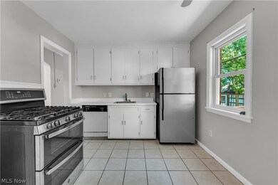 Kitchen featuring stainless steel appliances, sink, white cabinetry, and light tile floors